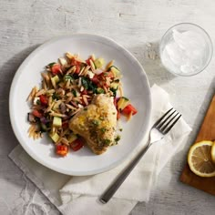 a white plate topped with chicken and veggies next to a glass of water