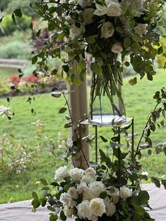 a vase filled with white flowers sitting on top of a table next to a green field