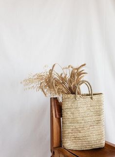 a wicker basket sitting on top of a wooden table next to a white wall