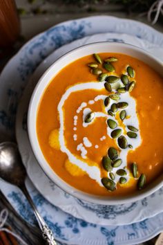 a bowl of carrot soup with cream and pumpkin seeds