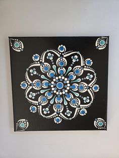 a black and white painting with blue flowers on it's side hanging on a wall