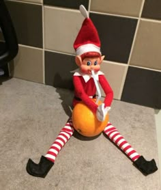 an elf is sitting on the floor with his legs spread out and holding a ball