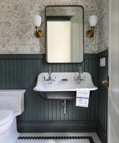 a white sink sitting under a bathroom mirror next to a black and white tiled floor