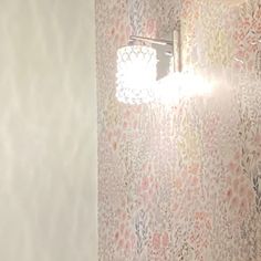 a bathroom with floral wallpaper and a light on the side of the shower head