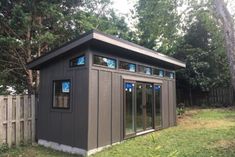 a small gray shed sitting in the middle of a yard