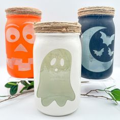 three painted jars with halloween decorations on them