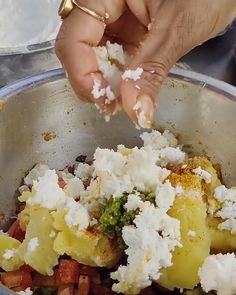 a person is scooping something out of a bowl filled with vegetables and feta cheese