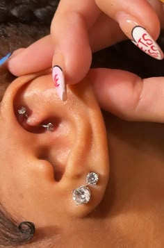 a woman is getting her ear decorated with white and red nail art designs on it