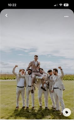 a group of men standing on top of each other in front of a lush green field