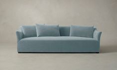 a light blue couch with four pillows on the back and one arm folded up in front