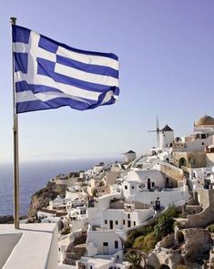 a greek flag flying on top of a building next to the ocean