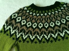 a green sweater with white and black designs on it