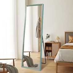 a large mirror sitting on top of a wooden floor next to a bed and chair