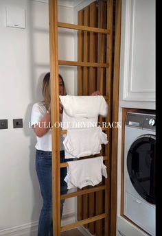 a woman standing in front of a washer and dryer next to a wooden ladder