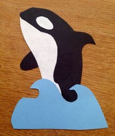 an orca jumping out of the water on top of a piece of blue paper