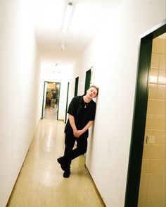 a man leaning against the wall in an empty hallway