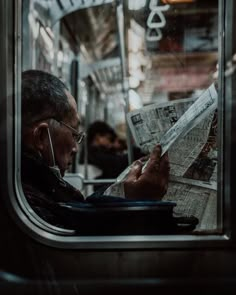 a man reading a newspaper while riding on a train