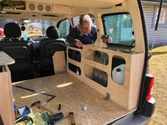 a woman sitting in the back of a van with her hand on the door handle