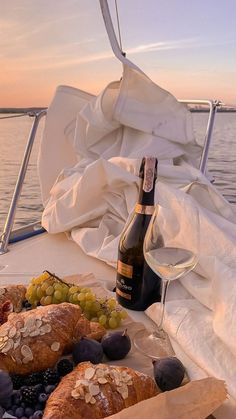 bread, grapes and wine on a boat with the sun setting in the distance behind it