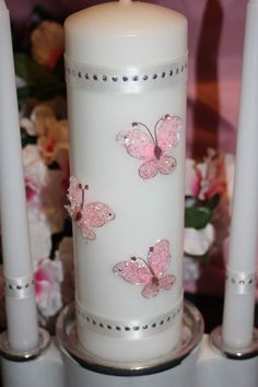 three white candles with purple butterflies on them