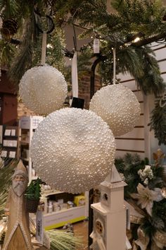 christmas decorations hanging from the ceiling in a store with pine cones and white balls on them