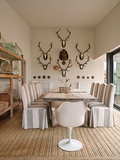 a dining room table with chairs and deer heads on the wall