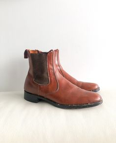 "Vintage 90s brown leather chelsea boots. Featuring elastic ankles, rounded toe, stacked heel, pull tabs for easy pull on kick off.  Handsome boots for a smart someone.  Label: The MacFarlane Fits Like: marked mens 9.5 Color: browns Fabrication: leather Condition: distressed vintage condition, some splash marks, scratches, lots of life left! Made in England 12\" length of insole 7.25\" total height  1\" heel height 4\" ball of foot This item comes from a pet & smoke free building. For a look beh Retro Brown Boots With Leather Lining, Retro Fitted Brown Boots, Vintage Chelsea Boots With Leather Sole, Vintage Leather Chelsea Boots With Round Toe, Fitted Vintage Brown Leather Boots, Vintage Leather Chelsea Boots With Snip Toe, Vintage Brown Leather Chelsea Boots, Brown Leather Chelsea Boots, Suede Fringe Vest