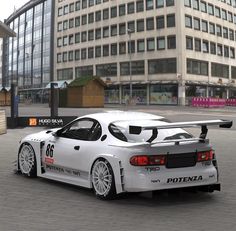 a white car parked in front of a tall building