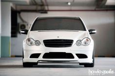 the front end of a white car parked in a garage