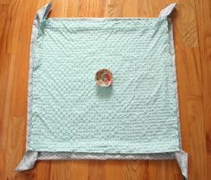 a blue quilted placemat with a flower on it sitting on a wooden floor