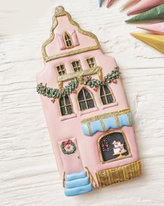 a pink and gold christmas house ornament on a white table with other decorations