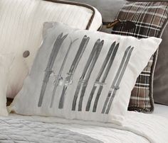 a white bed topped with pillows covered in different types of knifes and knives on it