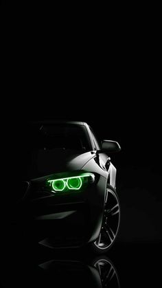 the front end of a black car with green lights