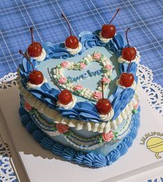 a heart shaped cake with cherries on top sitting on a table next to a book