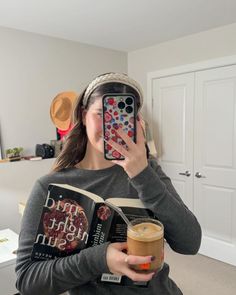 a woman taking a selfie with her cell phone while holding a cup of coffee