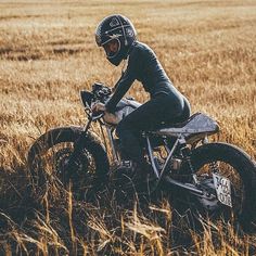 a man riding on the back of a dirt bike through a grass covered field,