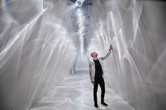 a man standing in the middle of a tunnel with white walls and lights on either side