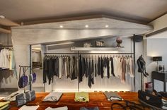 an open closet with clothes on hangers and shoes hanging from the ceiling in front of it