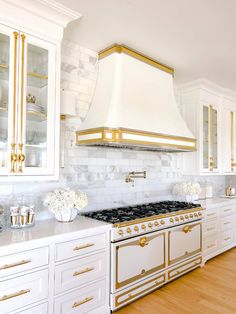 a kitchen with white cabinets and gold trim on the hood above the stove is shown