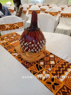 a vase sitting on top of a table covered in white linens and orange napkins