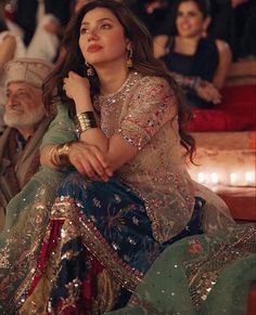 a woman sitting on top of a chair next to a man in a turban