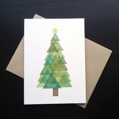 a card with a green christmas tree on it sitting on top of a wooden table