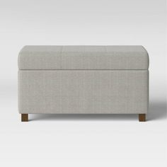 an upholstered footstool with wooden legs and a light gray fabric cover