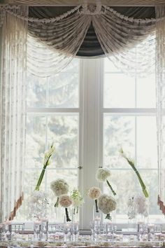 a table with vases and flowers on it in front of a window