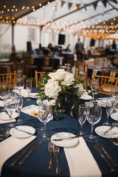 the table is set with white flowers and place settings for dinner or other special event