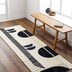 an area rug with black and white designs on it next to a wooden bench in a room