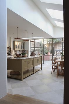 an open kitchen and dining room area with skylights in the ceiling, white tile flooring