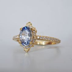 an oval shaped blue and white sapphire ring with diamond accents in yellow gold plated setting