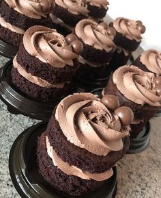 several chocolate cupcakes with frosting on black plates