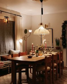 a dining room table and chairs with lights hanging from it's ceiling above them